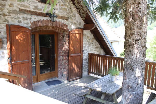 Una cabaña rústica de madera con fachada de piedra, una puerta de madera y un banco en el porche.