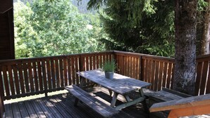 A wooden deck with a picnic table and benches, surrounded by trees.