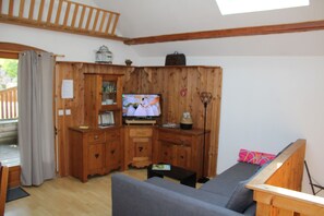 Un salón con paneles de madera, televisor, sofá y una mesita.