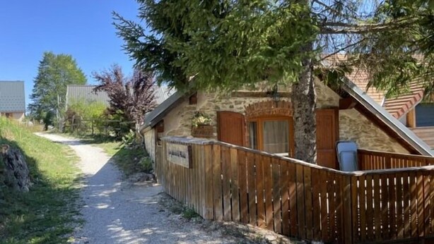 A gravel path leading to a rustic building with a wooden fence and a stone wall.
