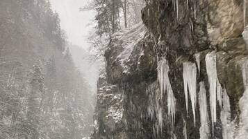 Une route enneigée, avec des glaçons pendants d’une paroi rocheuse.
