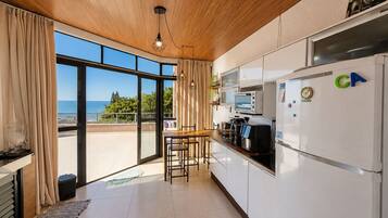 Una cocina moderna con vistas al mar, una zona de comedor y un amplio ventanal.