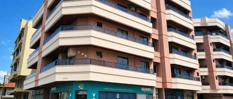A multi-story building with balconies, a storefront with signage, and a parked scooter.