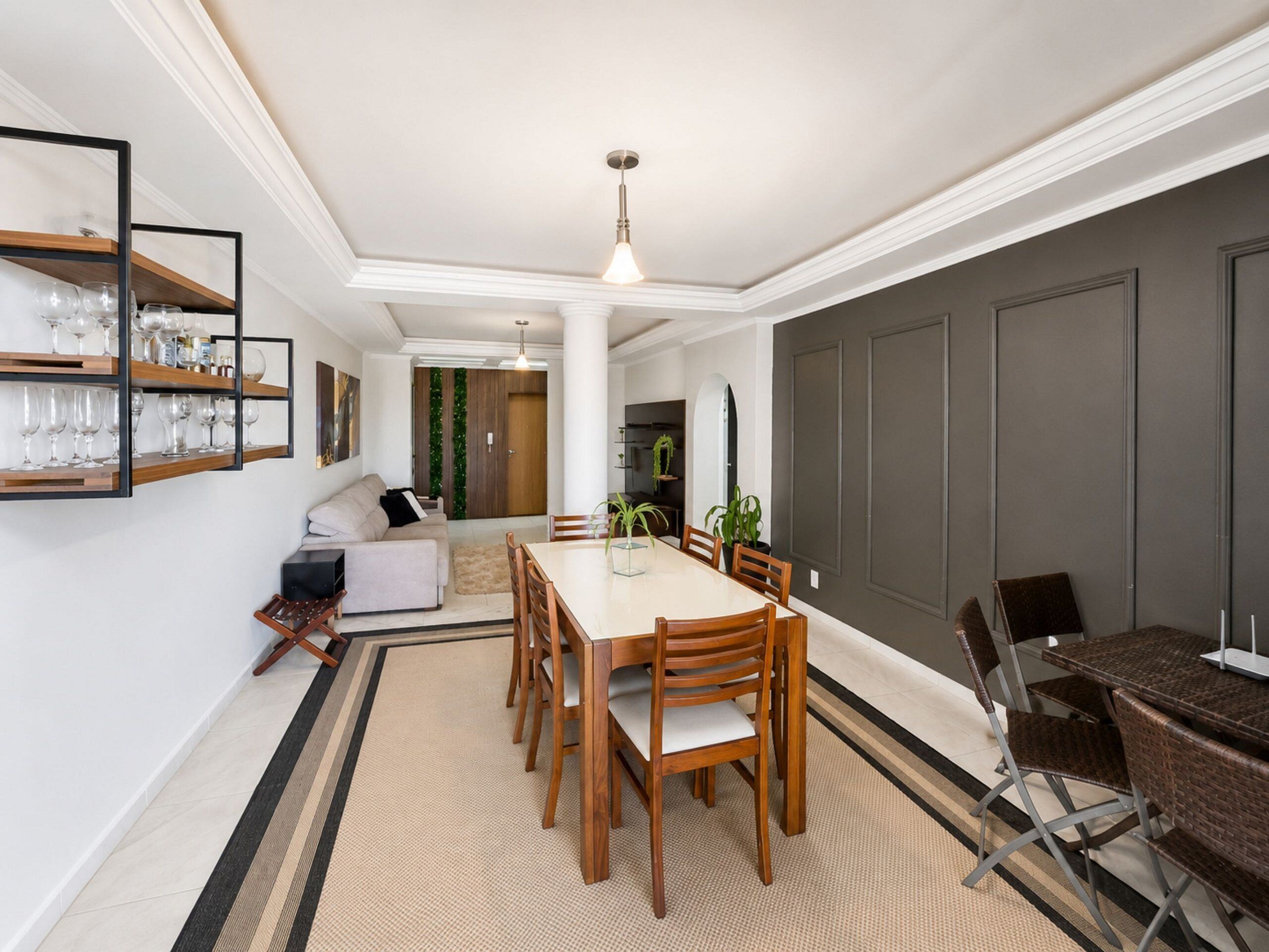 Uma sala de jantar com uma mesa e cadeiras de madeira, um sofá e uma mesa de centro.