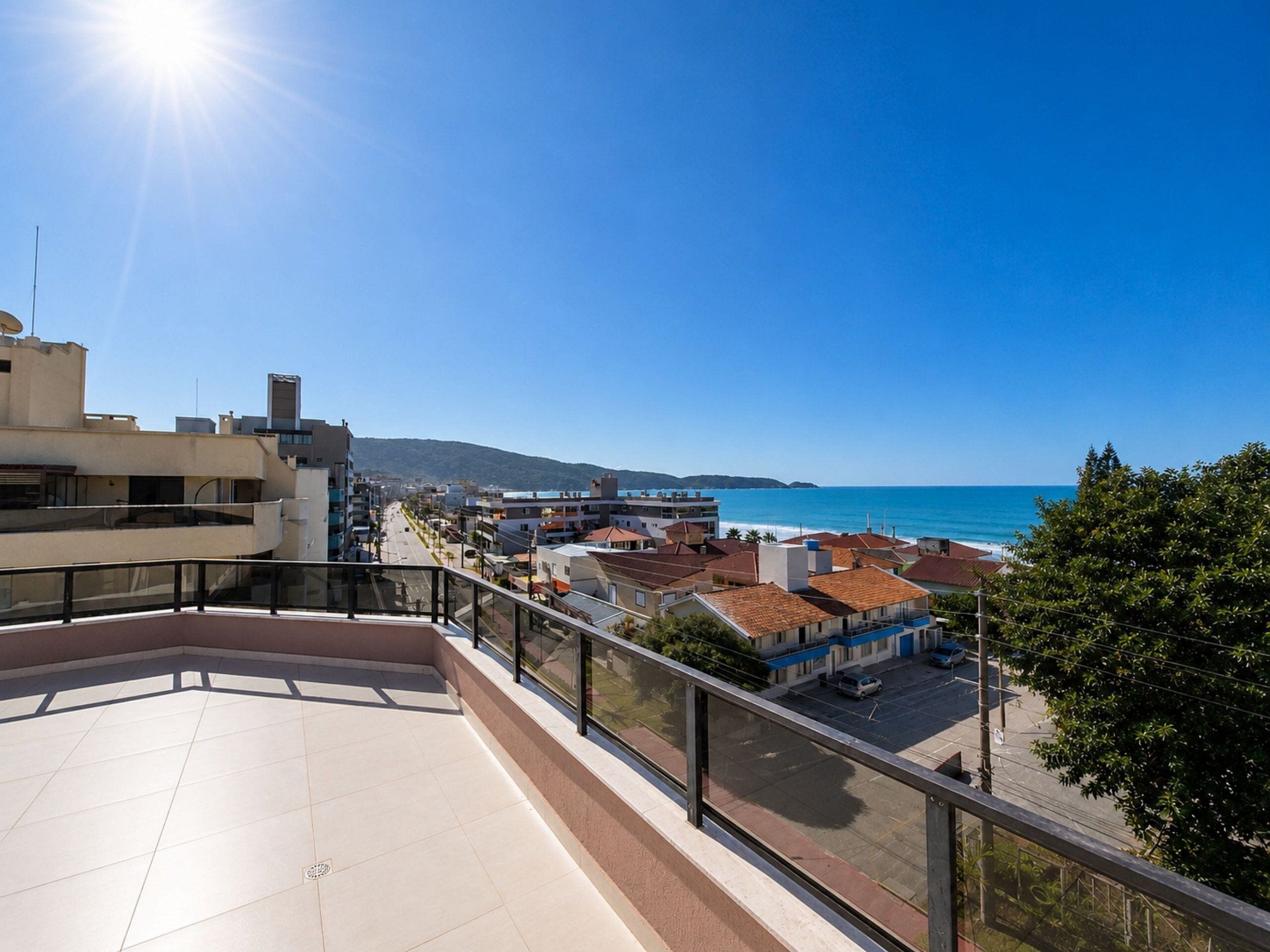 A rooftop terrace with a clear view of the sea and buildings.