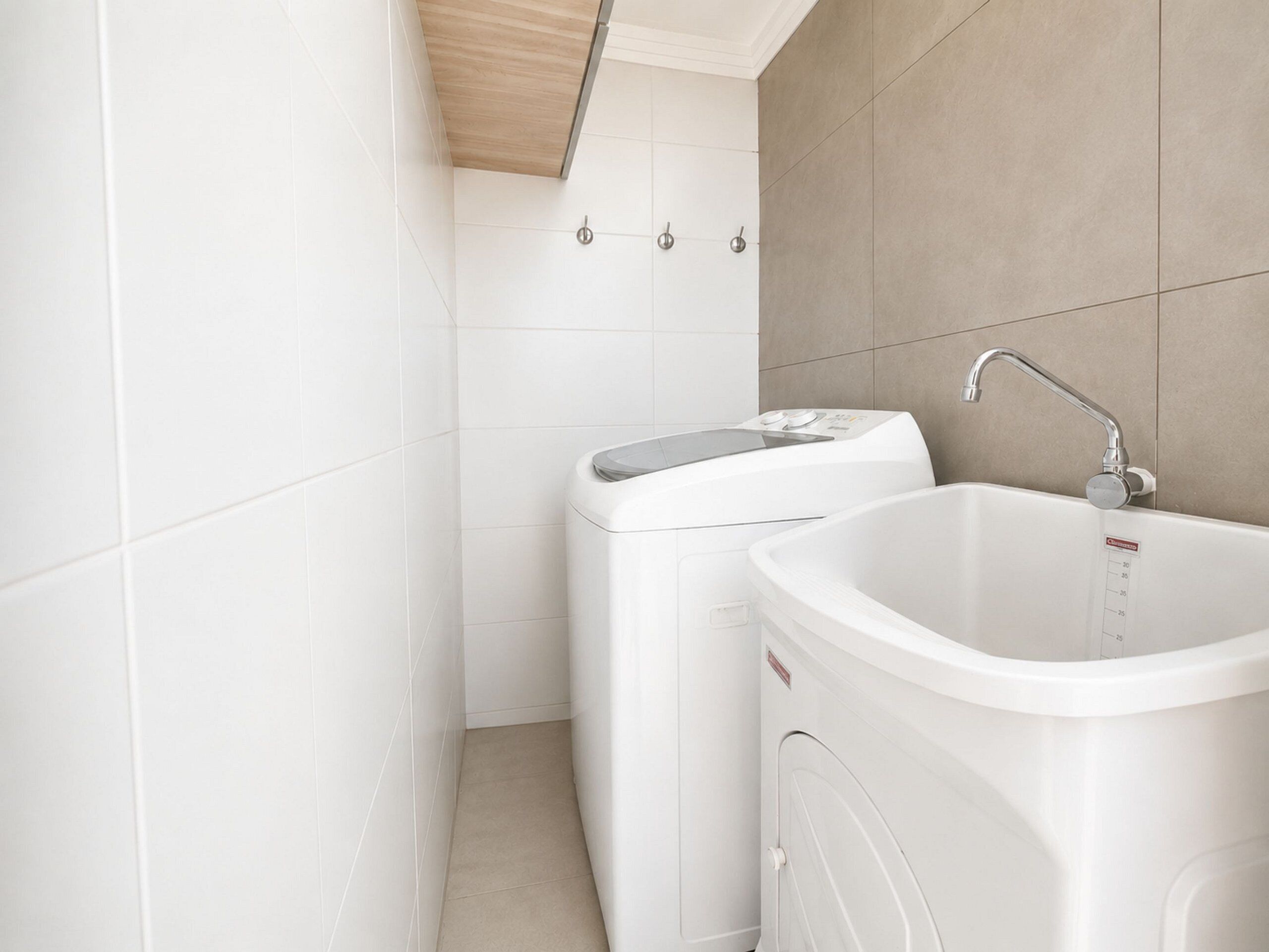 A bathroom with a washing machine, a sink, and a shower.