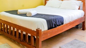 A single bed with a wooden frame, white bedding, and a grey curtain. - Cijana Gardens - School lane 1 br Westlands (Nairobi)