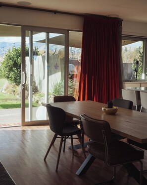 Comedor con una mesa grande, sillas y vistas a través de un ventanal corredero.