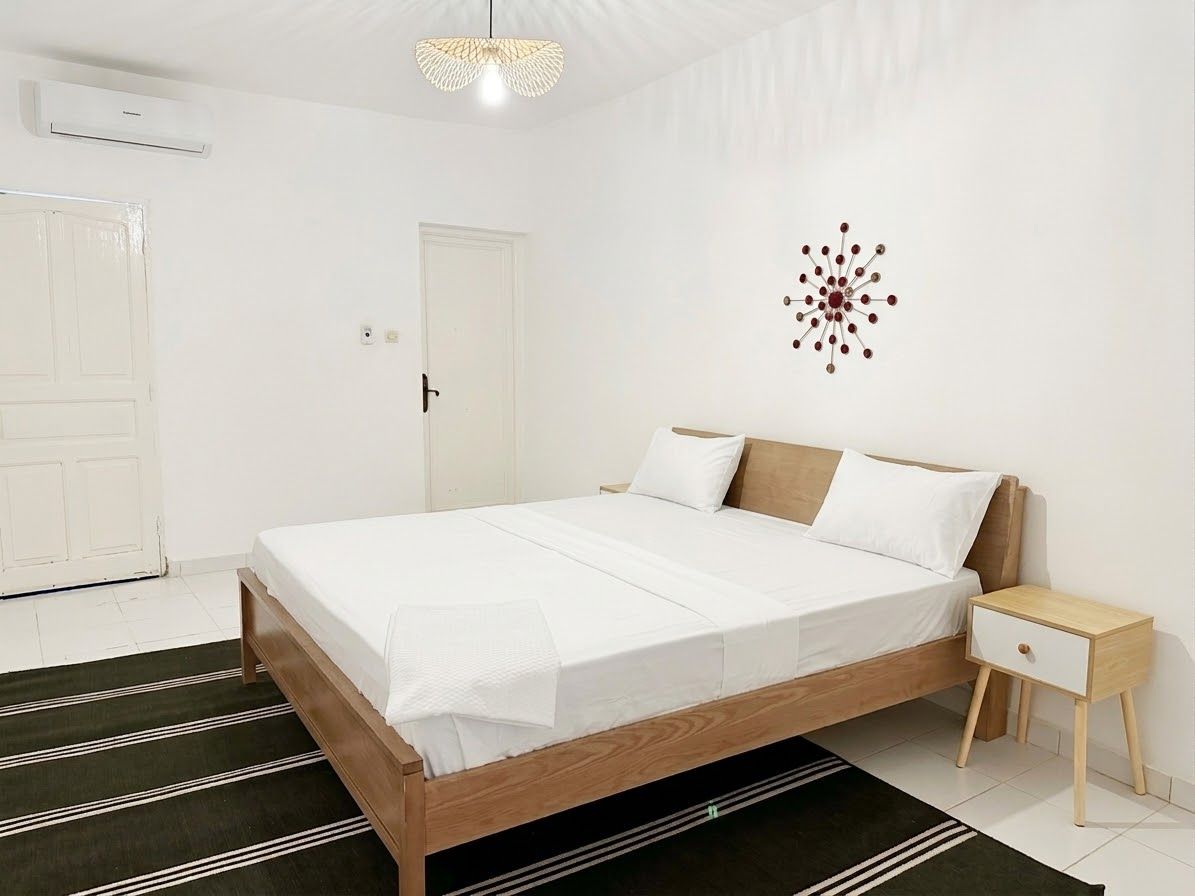 A bedroom with a bed, bedside table, and a wall decoration.