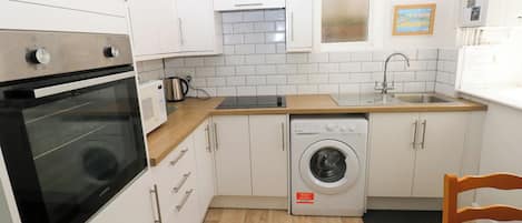 A compact kitchen with a built-in oven, microwave, and washing machine.