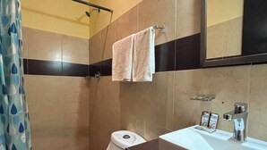 Een badkamer met toilet, wastafel, spiegel en douchegordijn.
