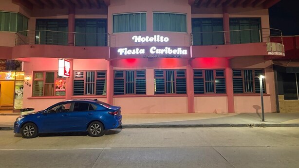 Een roze gebouw met een bord waarop staat 'Hotelito Fiesta Caribeña'.