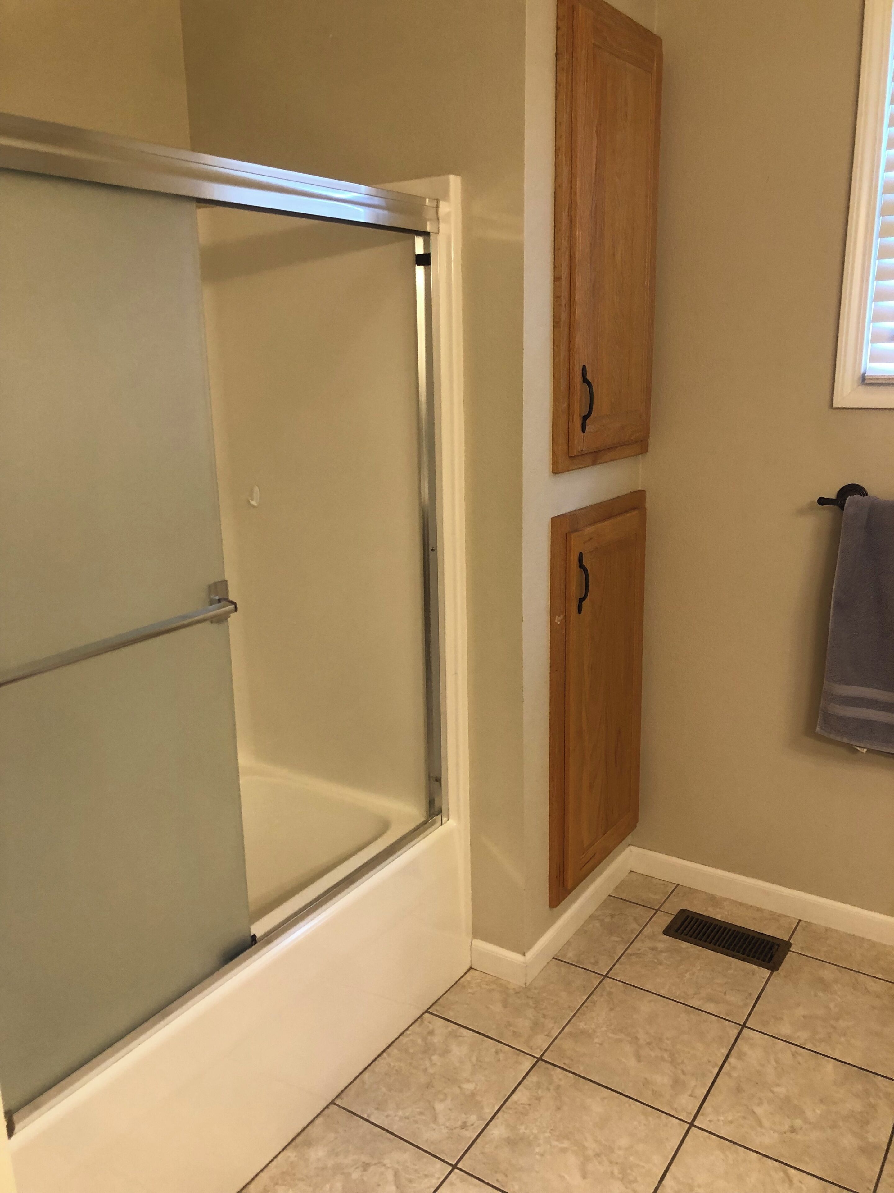Baño con cabina de ducha de vidrio, armarios de madera y un perchero para toallas.