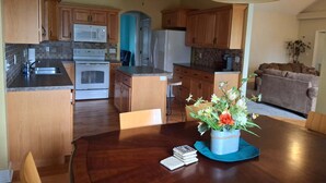 A kitchen with wooden cabinets, a microwave, an oven, and a dining area with a table and chairs. - Walk to State Fairgrounds & Katy Trail, 4BR Home by Park (Sedalia)
