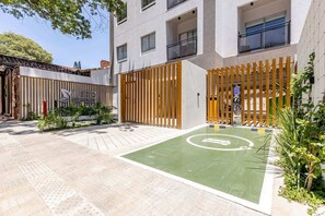 A courtyard with a green play area, a wooden fence, and a building with balconies. - Life Recoleta (Asunción)