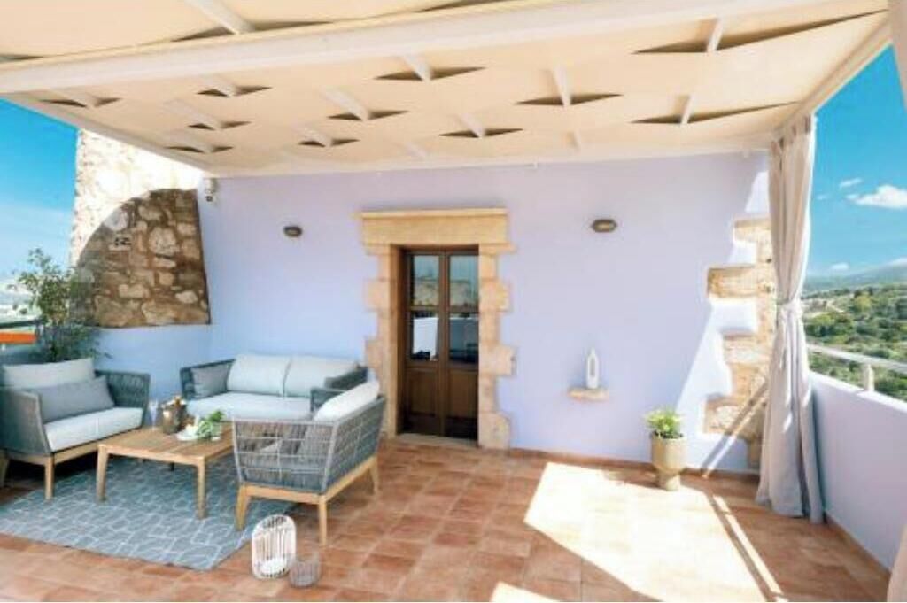 A balcony with a seating area, a stone wall, and a view of the landscape.