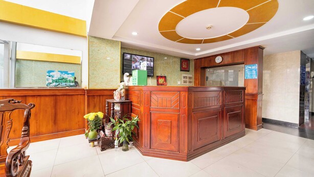 A reception area with a wooden reception desk, a clock, and a television mounted on the wall. - Collection O Thanh Van Hotel - Binh Tan (Ho Chi Minh City)