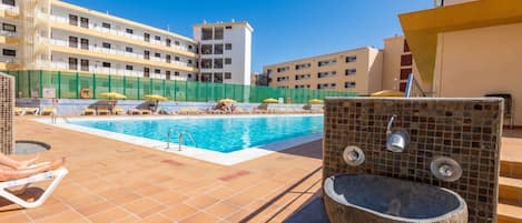 Un área de piscina con sillas de descanso y una pila de piedra.