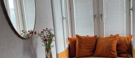 Une pièce avec un banc en bois, une table bleue et un miroir au mur.