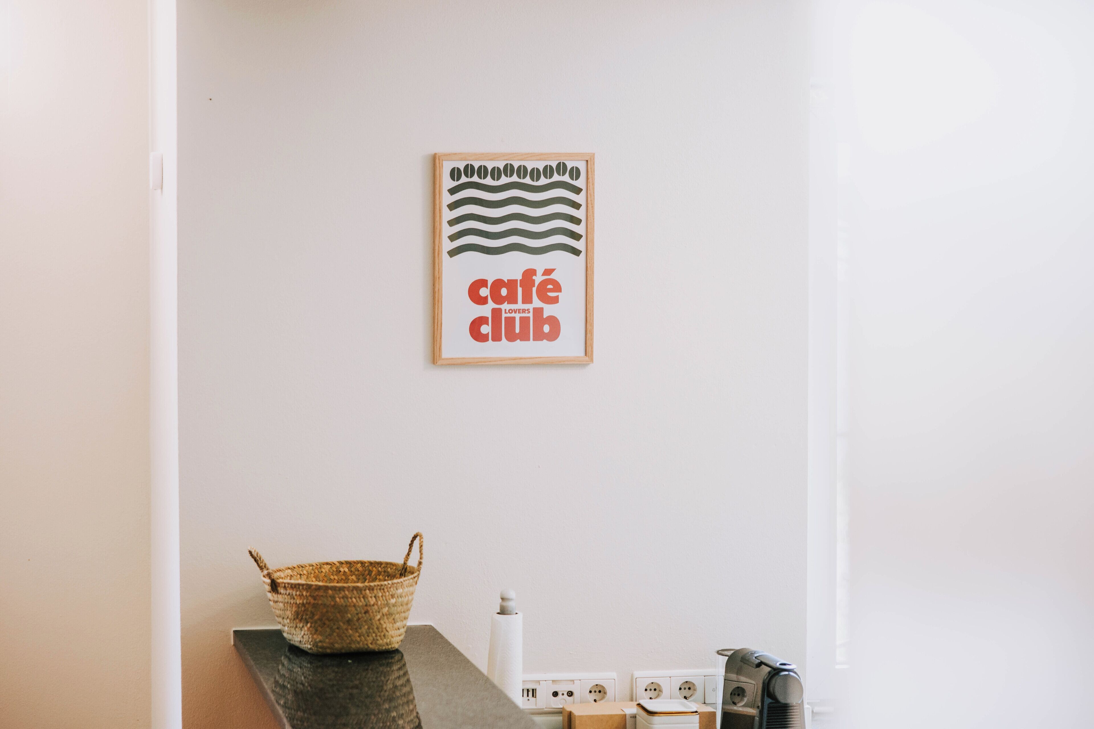 Una pared con un cartel enmarcado que dice 'café club' y una cesta tejida sobre un mostrador.