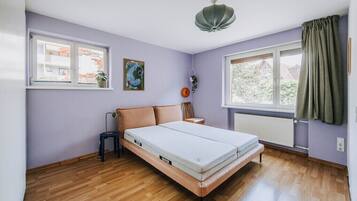Una habitación con cama, ventana, radiador y luz en el techo.