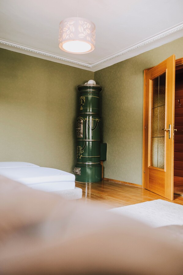 Una habitación con un objeto cilíndrico verde, una puerta de madera y una cama blanca.
