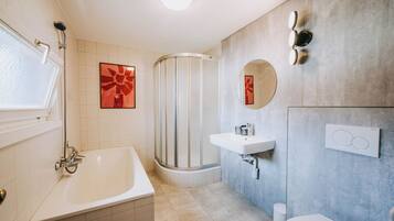 A modern bathroom with a bathtub, a shower, a sink, and a toilet.