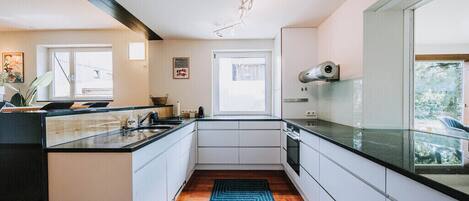 A modern kitchen with a central island, white cabinetry, and a blue patterned rug.