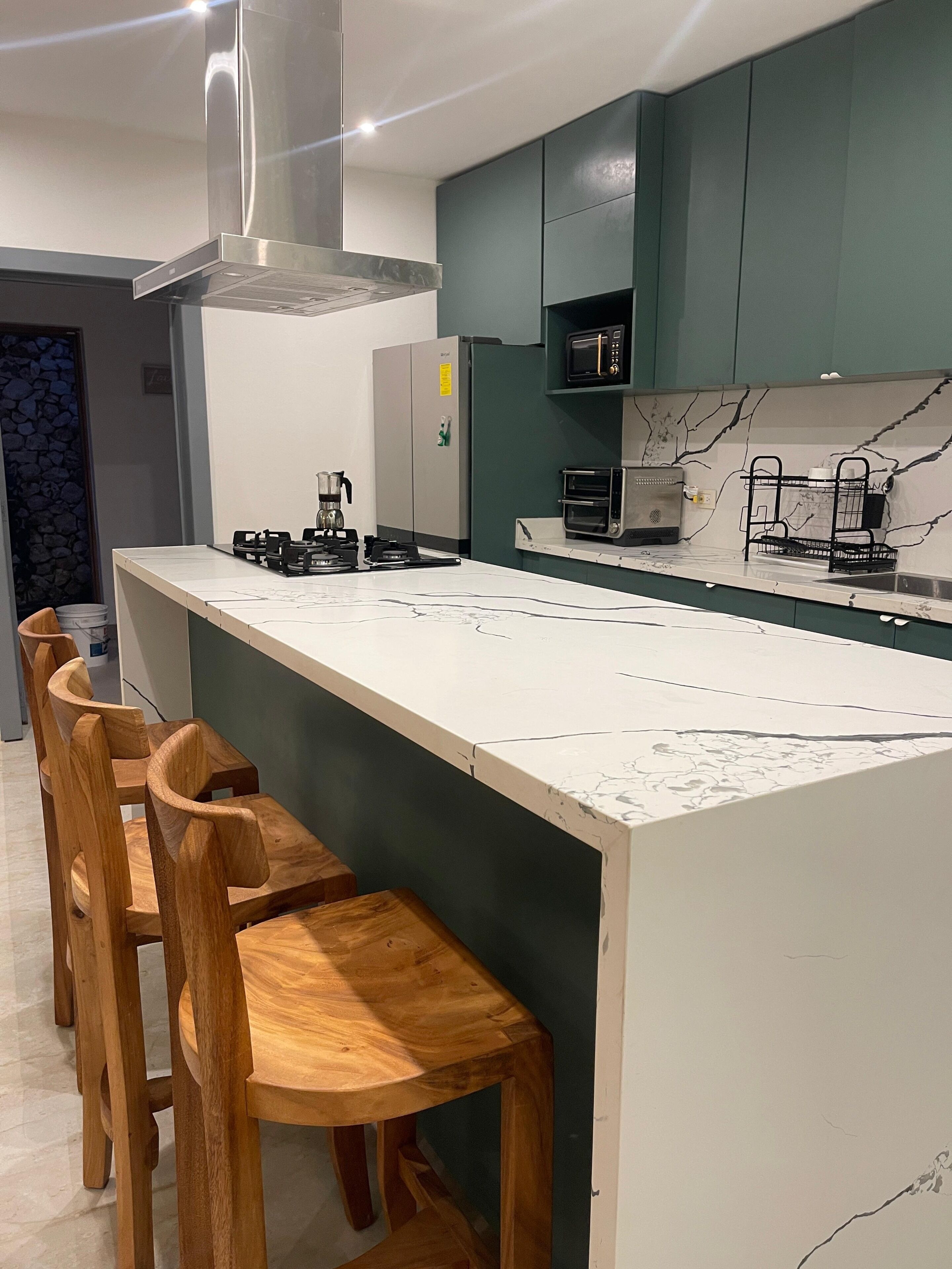 A modern kitchen with a central island, bar stools, a built-in oven, and a microwave.