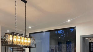 A modern dining area with a wooden table, woven placemats, and a hanging light fixture. - Spacious 4-bedroom house in adorable Cabrera with AC and gym (Cabrera)