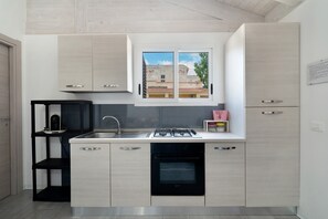 A modern kitchen with a built-in gas stove, a dishwasher, and a window with a view of buildings. - Casa Azzurra Beach – Beachfront Holiday Home with Direct Access (Reitani)
