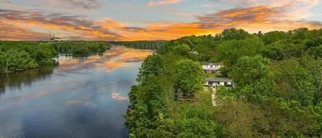 A riverside view with a house and dense greenery.
