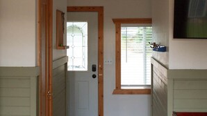 A narrow hallway with a wooden door, a small window, and a television mounted on the wall.