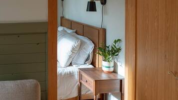 A bedroom with a bed, bedside table, lamp, and a chair.