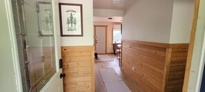A hallway with wooden paneling, a framed welcome sign, and a door leading to a room.
