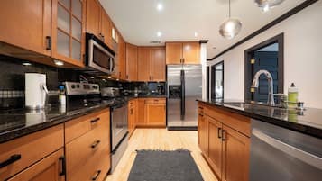 Una cocina moderna con armarios de madera, electrodomésticos de acero inoxidable y encimera negra.