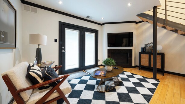 A modern living room with a checkered floor, a sofa, a coffee table, a fireplace, and a staircase. - 301-4thstreet-318 (Austin)