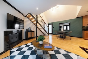 Ein zeitgemäßer Wohnbereich mit Treppe, Flachbildfernseher, Essbereich und Kamin.