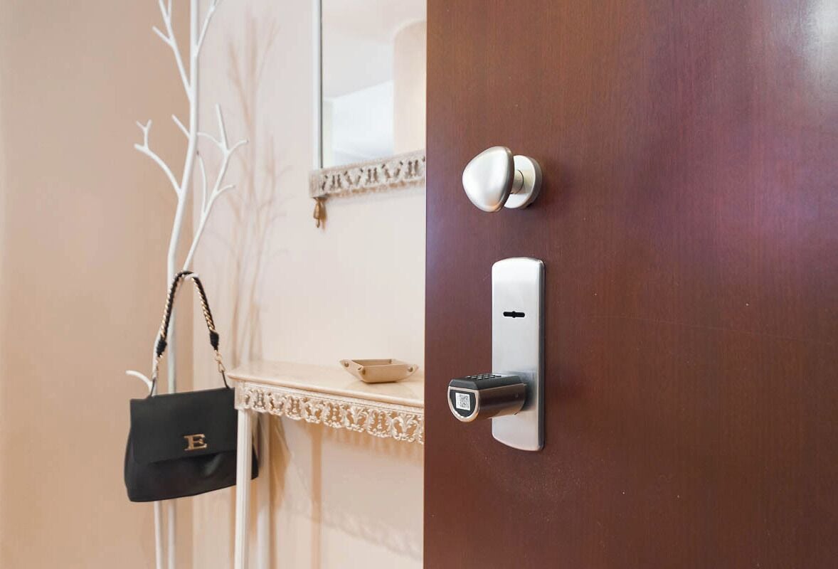 Puerta de habitación de hotel con lector de tarjeta, interruptor de luz en la pared y una pequeña mesa con un adorno.