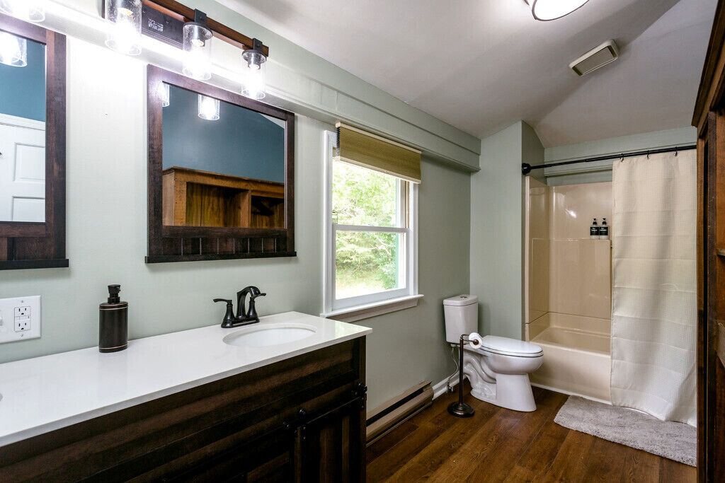 A bathroom with a white sink, a mirror, a toilet, and a shower area.