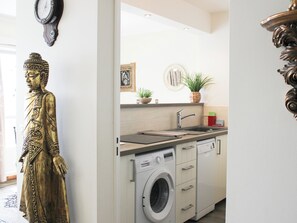 A kitchen with a washing machine, a sink, and a Buddha statue. - Paris 15 • NYC Vibes • 27th Floor (Paris)