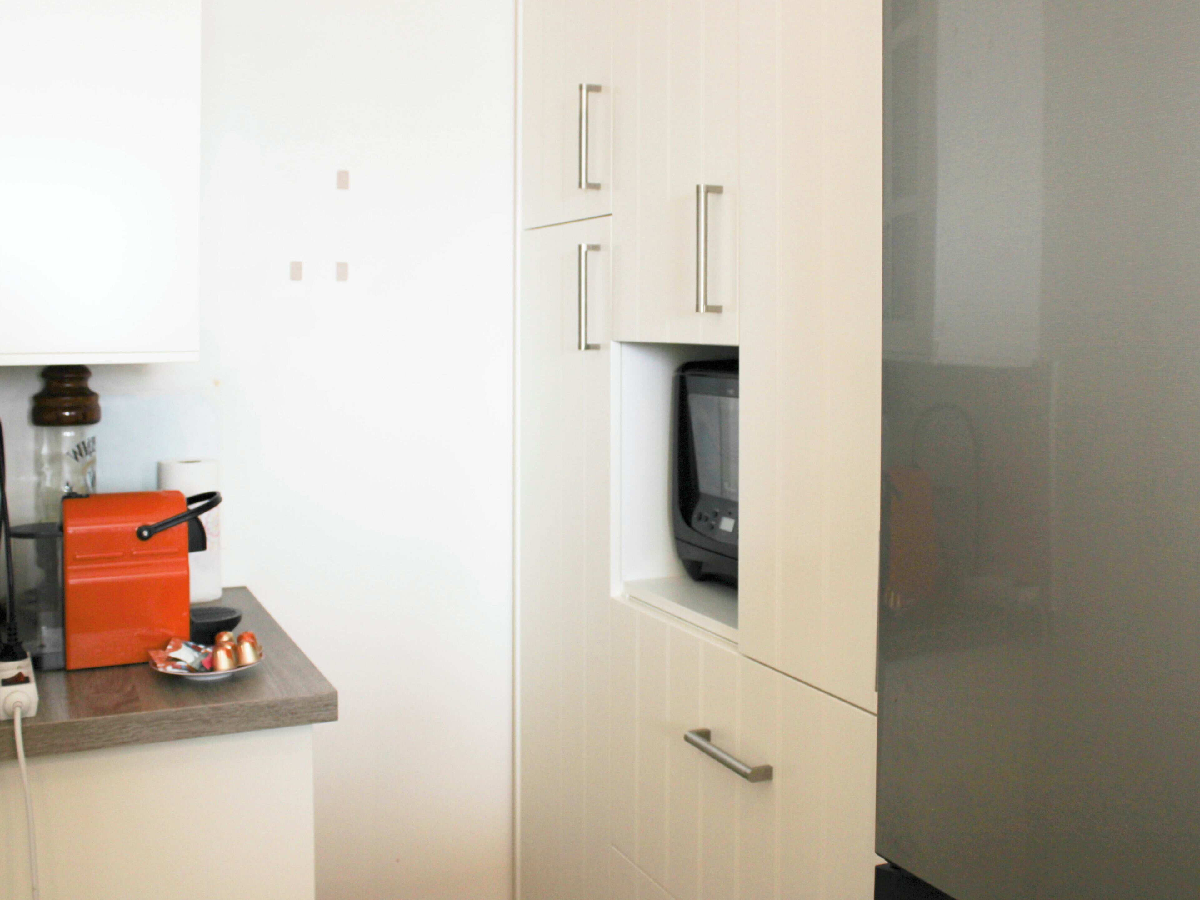 A kitchen with white cabinets, a microwave, and a red appliance on the counter.