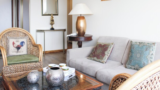 En stue med sofa, stol, sofabord, lampe og et spejl.