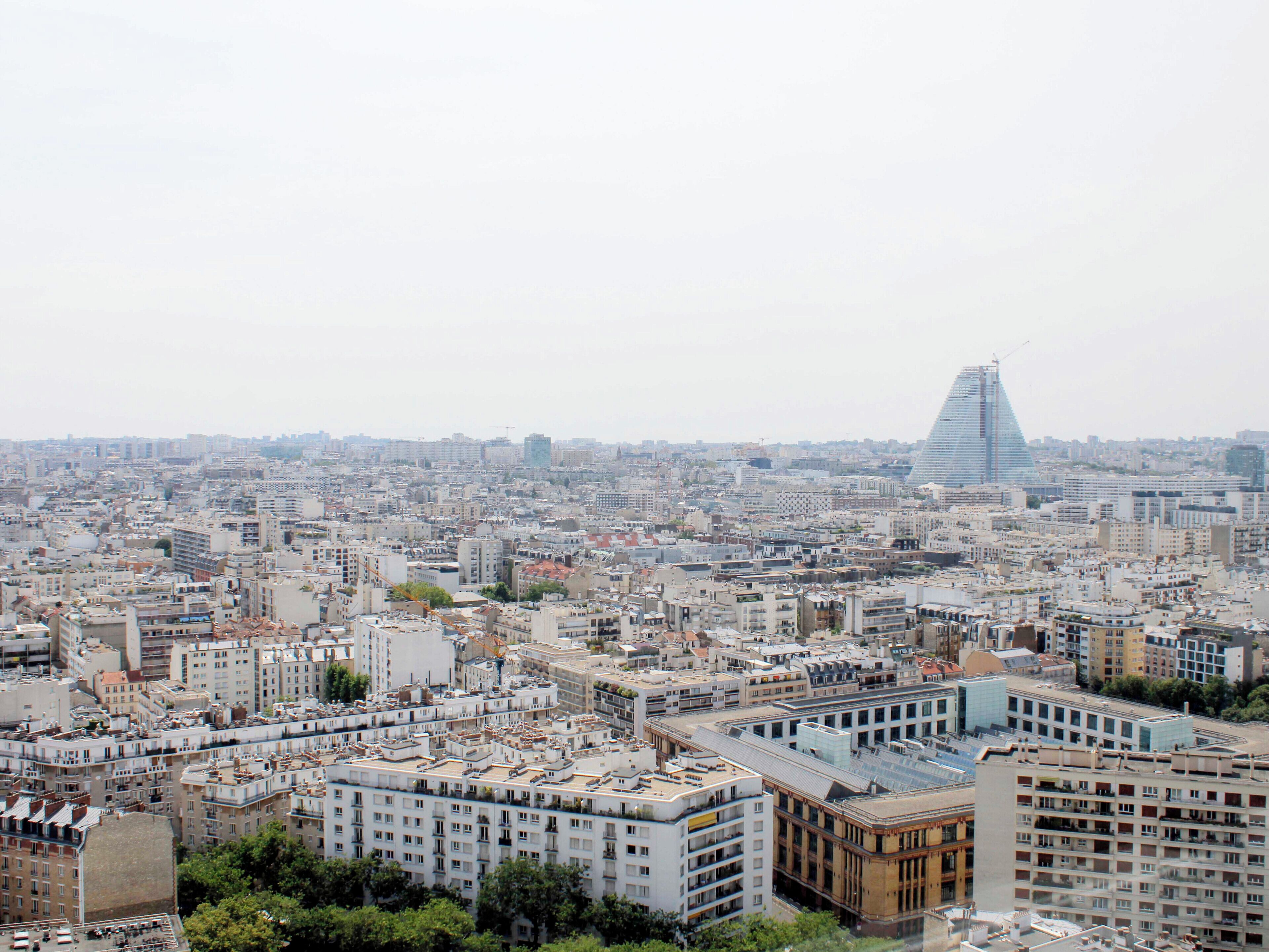 A densely packed urban cityscape with a variety of building structures, including a prominent triangular skyscraper.