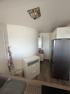 A compact kitchen with a refrigerator, a sink, and a cabinet. - Paris 15 • NYC Vibes • 27th Floor (Paris)