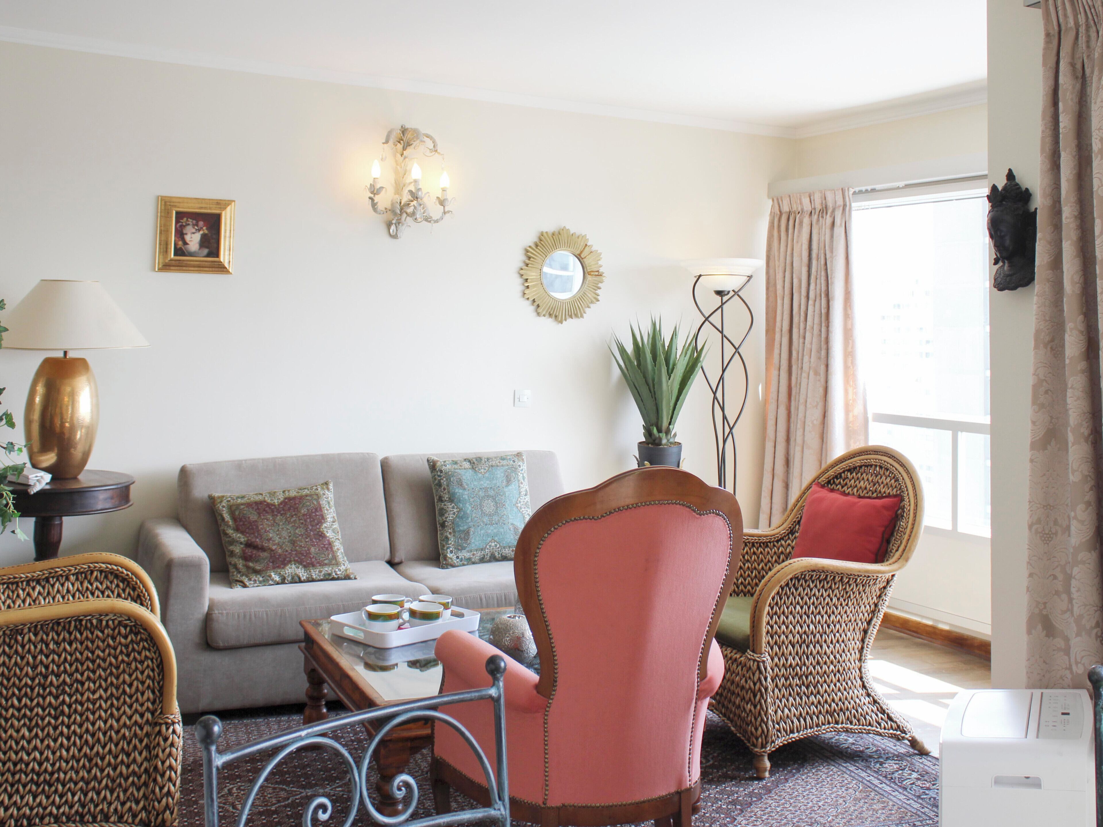 Een woonkamer met een bank, twee fauteuils, een salontafel en een lamp.