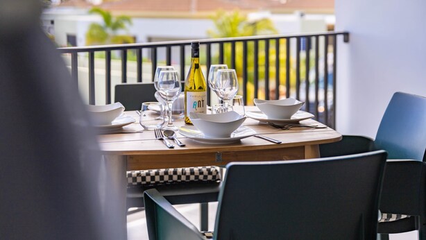 A dining table set with white plates, bowls, and wine glasses, with a bottle of wine on the table. - Felicidat Nobo, Mambo Beach (Willemstad)