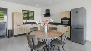 A modern kitchen with a round dining table, chairs, a refrigerator, and a built-in oven. - Felicidat Nobo, Mambo Beach (Willemstad)