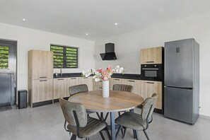 A modern kitchen with a round dining table, chairs, a refrigerator, and a built-in oven. - Felicidat Nobo, Mambo Beach (Willemstad)