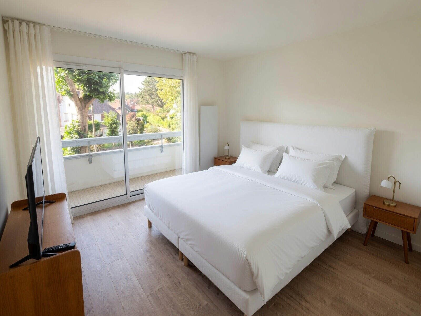 Une chambre d’hôtel avec un grand lit, une télévision, un bureau et un balcon donnant sur l’extérieur.